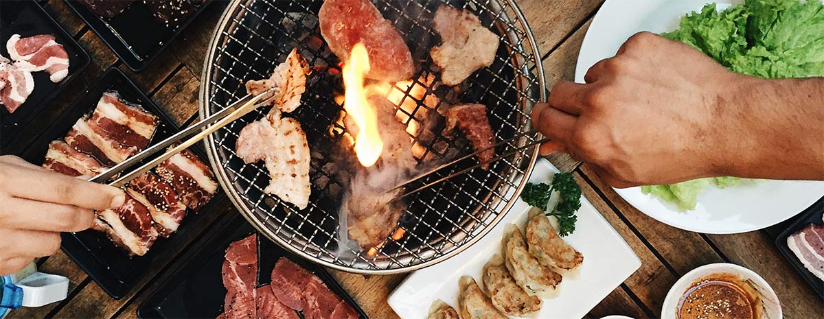 hands holding barbecuing meat grill with tongs